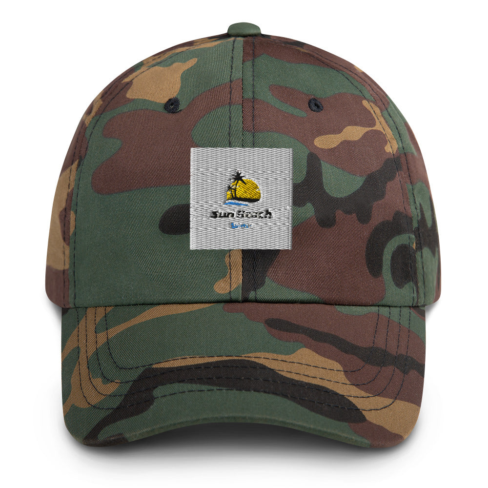 A camouflage base ball cap/dad hat with a sun and beach logo embroidered in light blue and yellow on the front. The hat is made of light-colored cotton fabric and has a curved brim. It has an adjustable strap at the back for a comfortable fit."