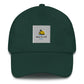 A green dad hat with a sun and beach logo embroidered in light blue and yellow on the front. The hat is made of light-colored cotton fabric and has a curved brim. It has an adjustable strap at the back for a comfortable fit."